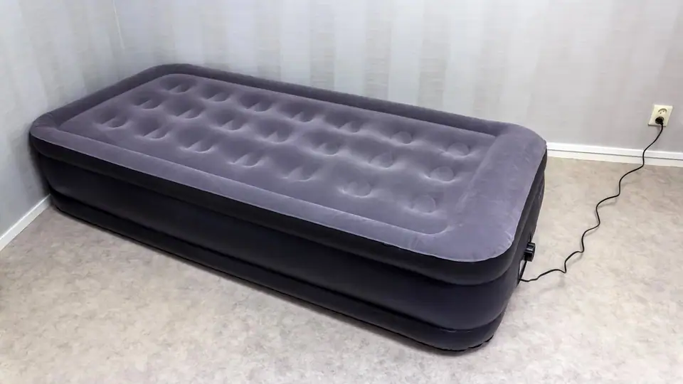 Inflated dark gray air mattress with a flocked velour top on a bedroom carpet