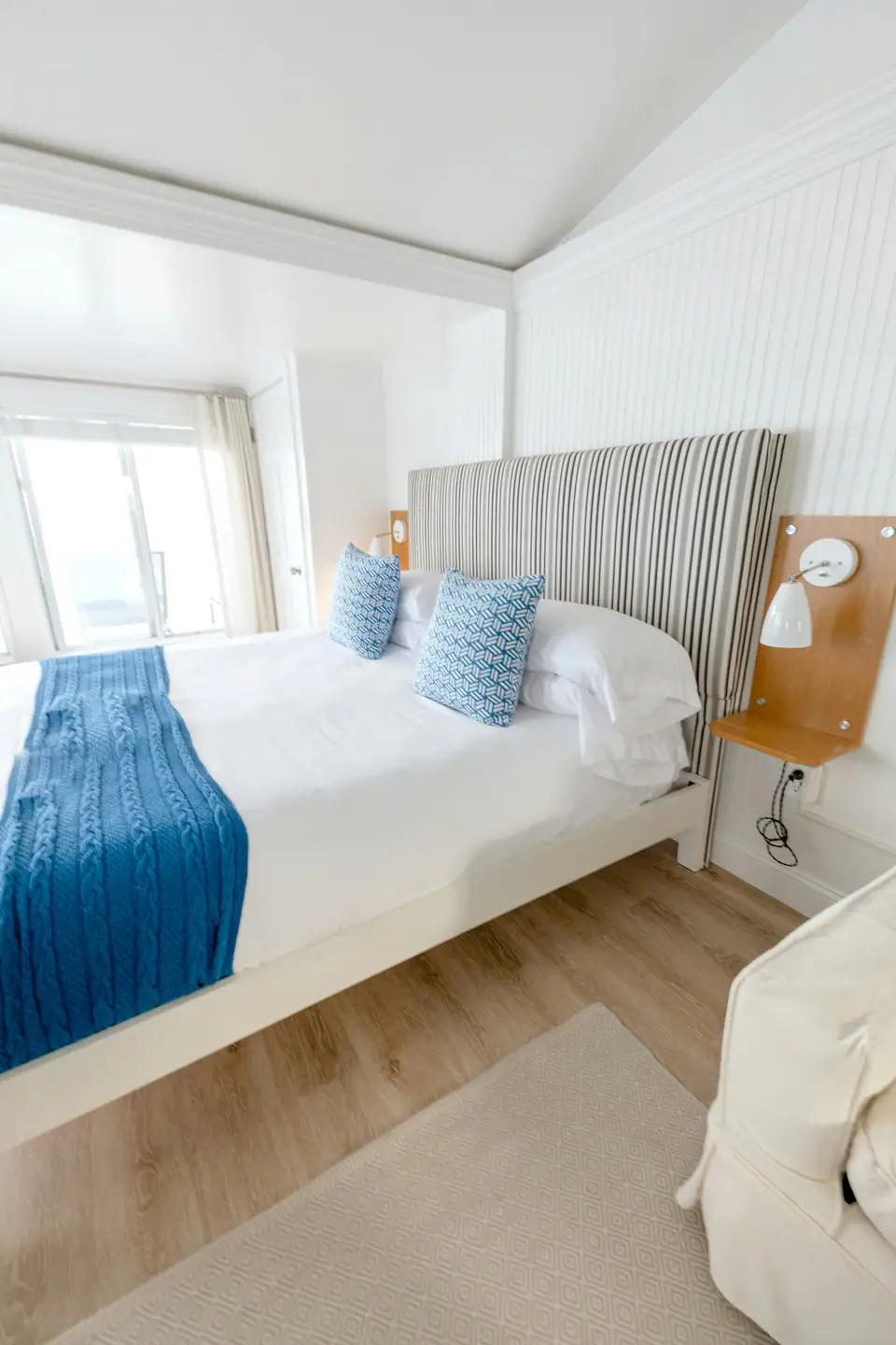 Made-up bed with blue pillows in a bright bedroom