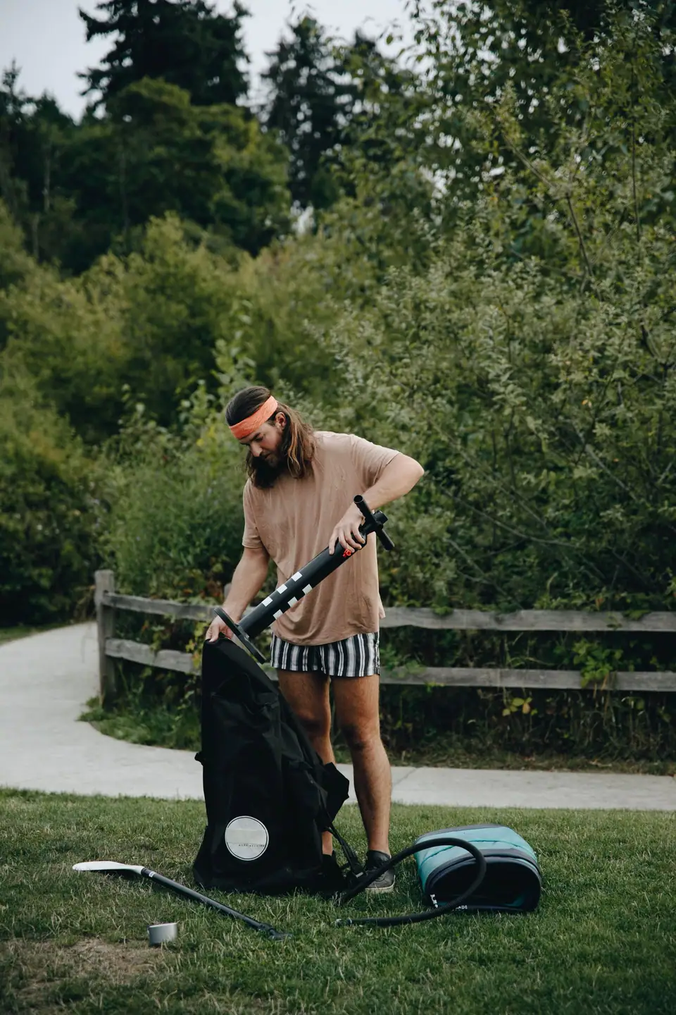 Man using a hand pump to inflate an air mattress in a park