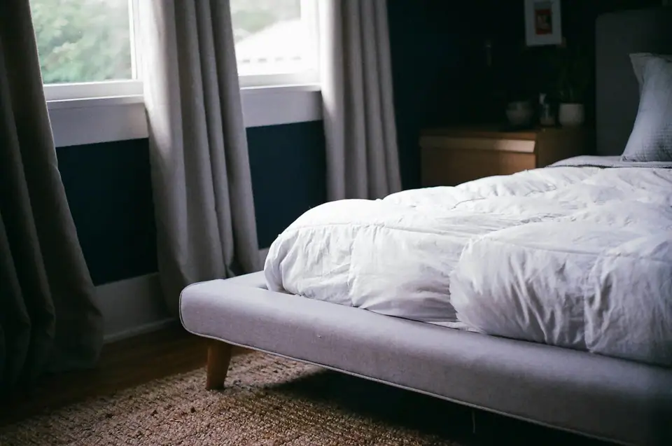 Low bed with a thick white duvet beside a window